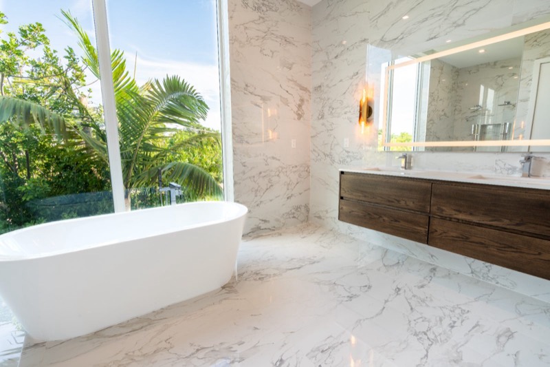 Marble master bathroom with floating oak vanity and freestanding tub, Fort Lauderdale FL