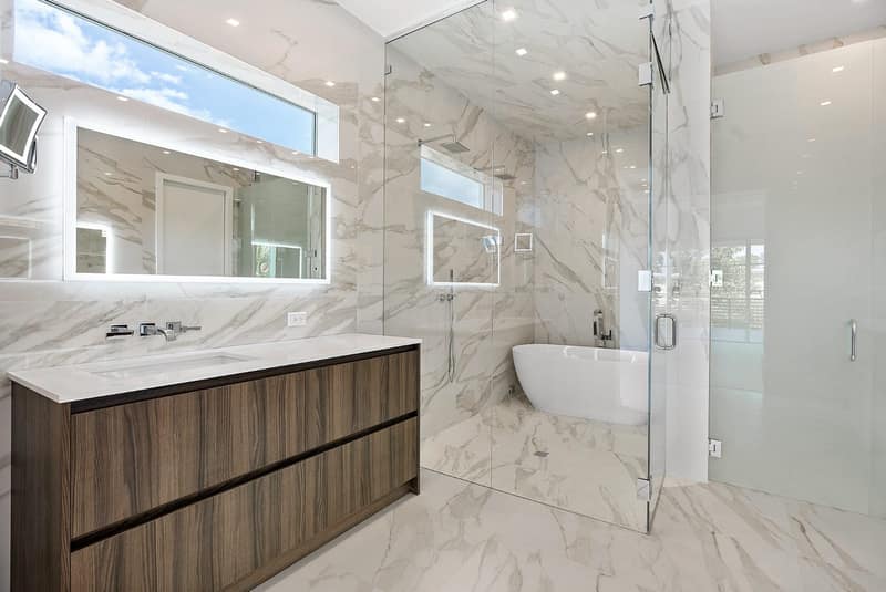 Contemporary master bath with backlit mirror and marble walls, Delray Beach FL